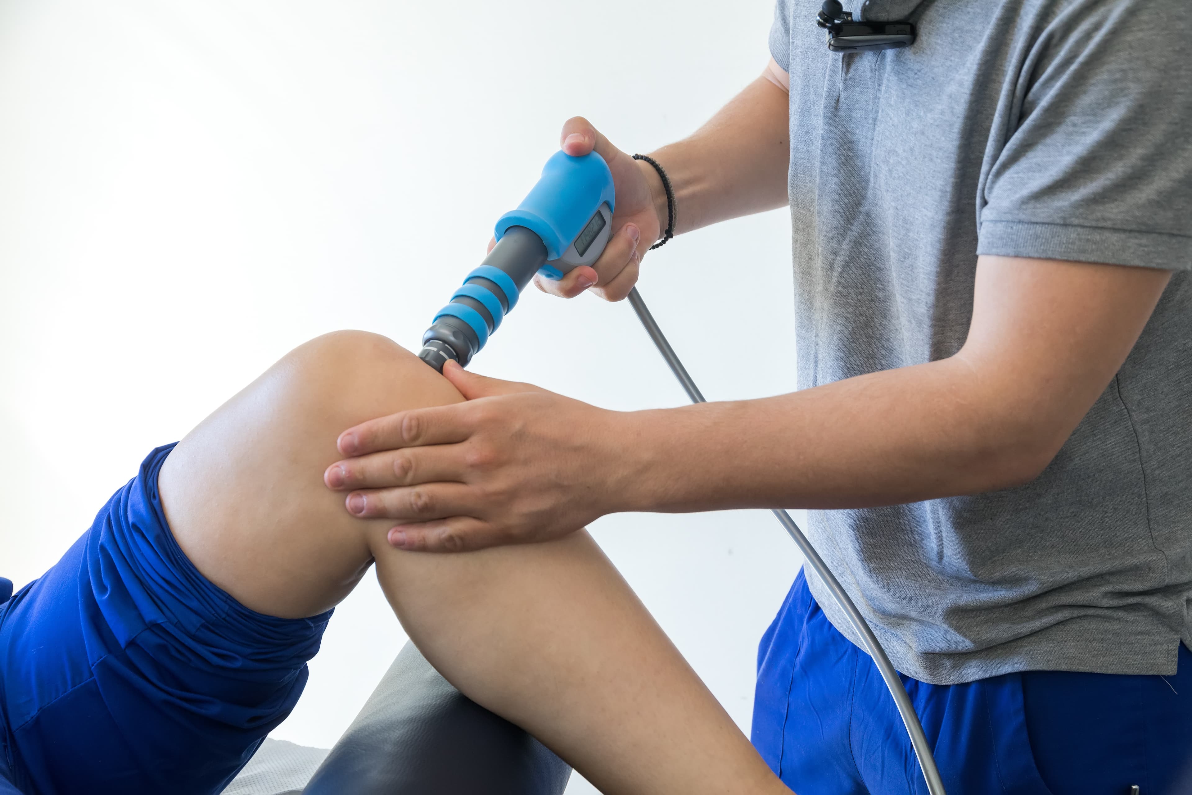 Therapist applying a radial shockwave device to a patient's knee